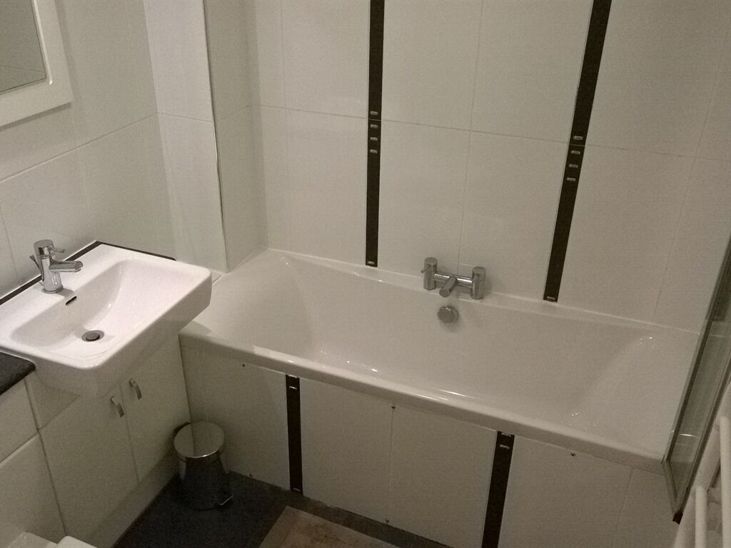 Kylpyhuone, jossa on valkoinen pesuallas, kylpyamme ja peili.