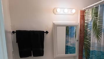 Un baño con inodoro, lavamanos y espejo sobre el lavamanos.