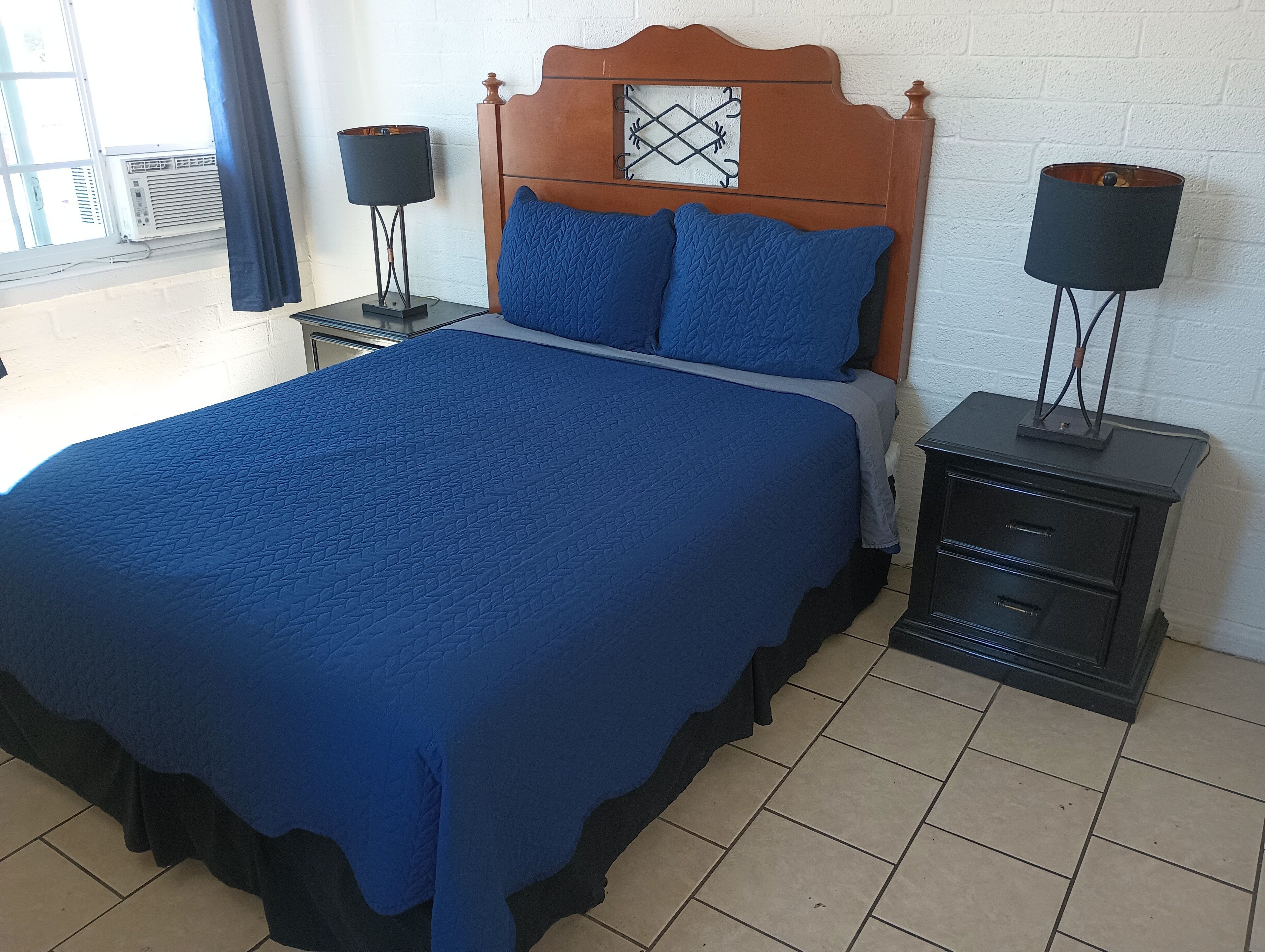A bedroom with a large bed, two bedside tables, and a window with curtains.