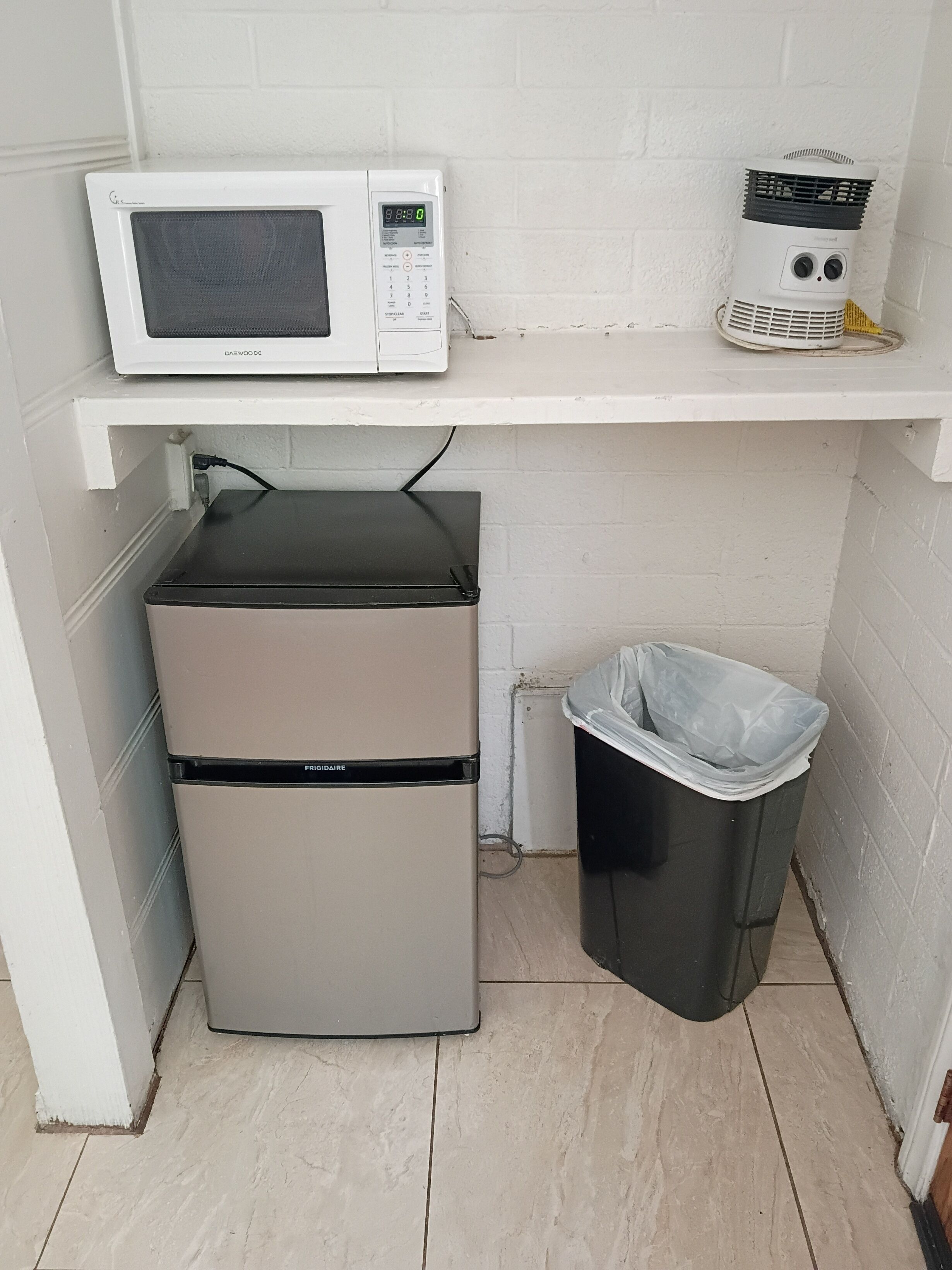 Une petite cuisine équipée d’un four à micro-ondes, d’un petit réfrigérateur et d’une poubelle.