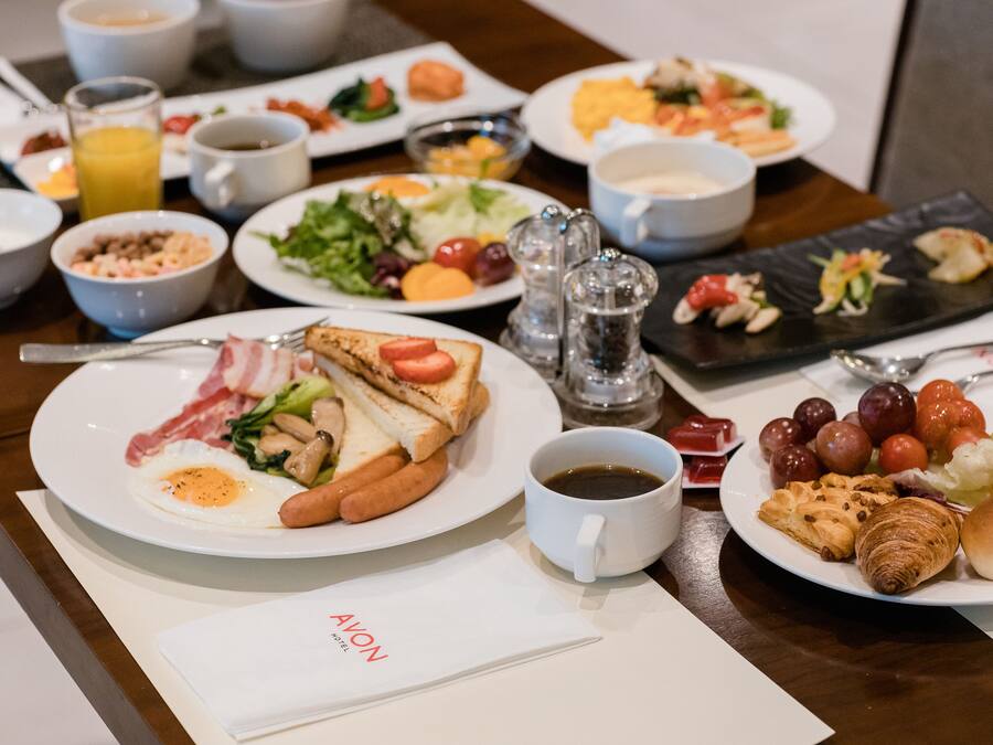 A breakfast buffet with various dishes, including eggs, meats, and fruits.