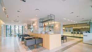 Un vestíbul d'hotel modern amb taulell de recepció, zona de seients i bar.