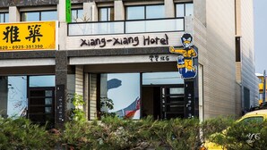 En hotels facade med skiltage for "Xiang-Xiang Hotel" og en tegneseriefigur.