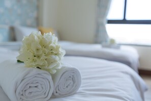 A neatly made bed with rolled white towels and a cluster of white flowers. - Xiang Xiang Hotel (Hengchun)