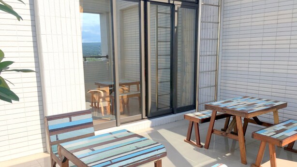 En terrasse med træmøbler og en glasdør, der fører til en balkon.
