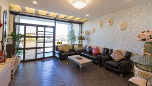 En rummelig opholdsstue med lædersofaer, et glashøjt bord og en lysekrone.