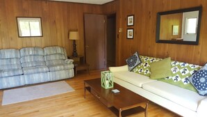 A living room with a sofa, a coffee table, a lamp, and a door.