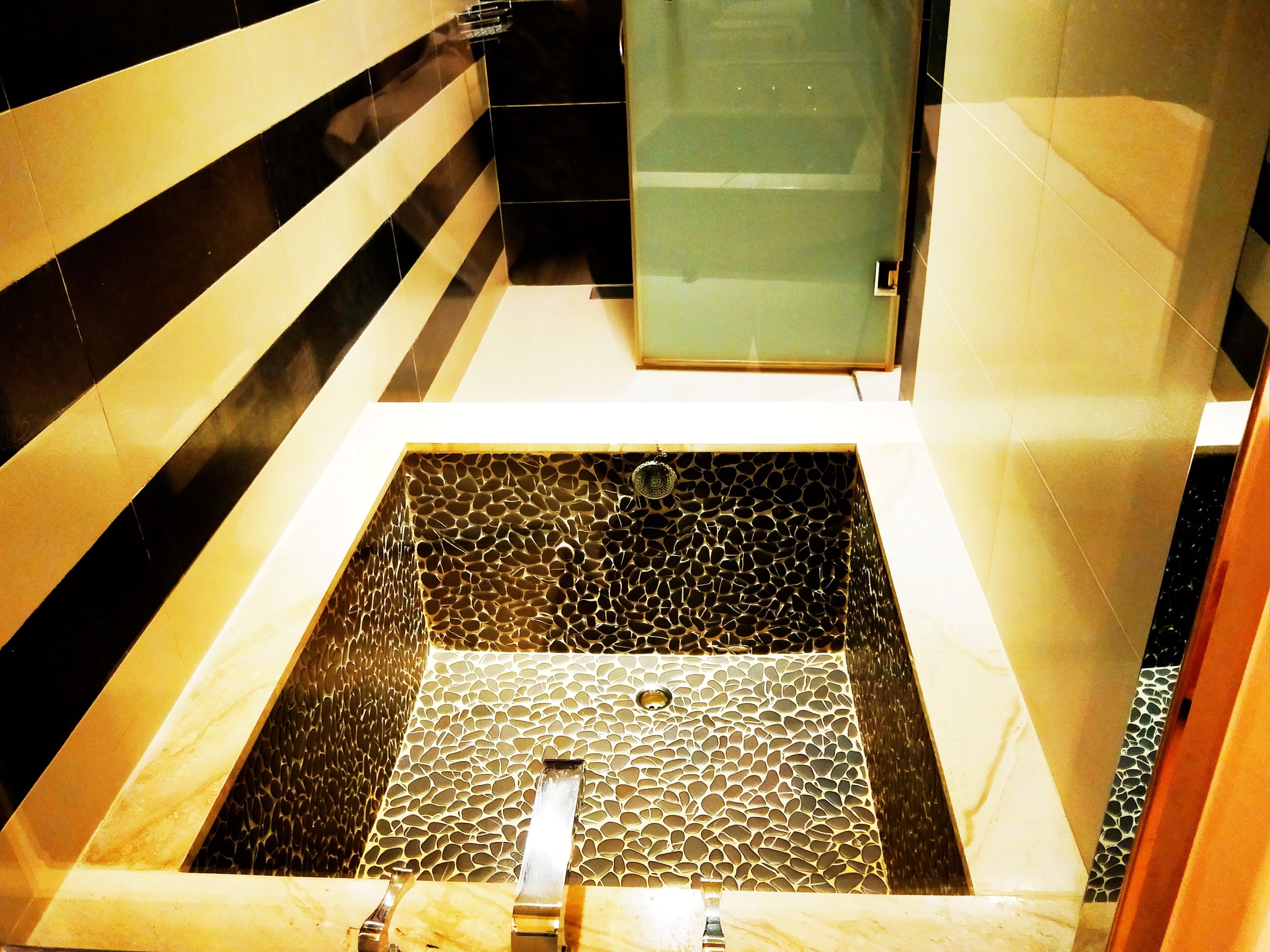 Un baño moderno con una bañera cuadrada, cabina de ducha de vidrio y suelo de baldosas.