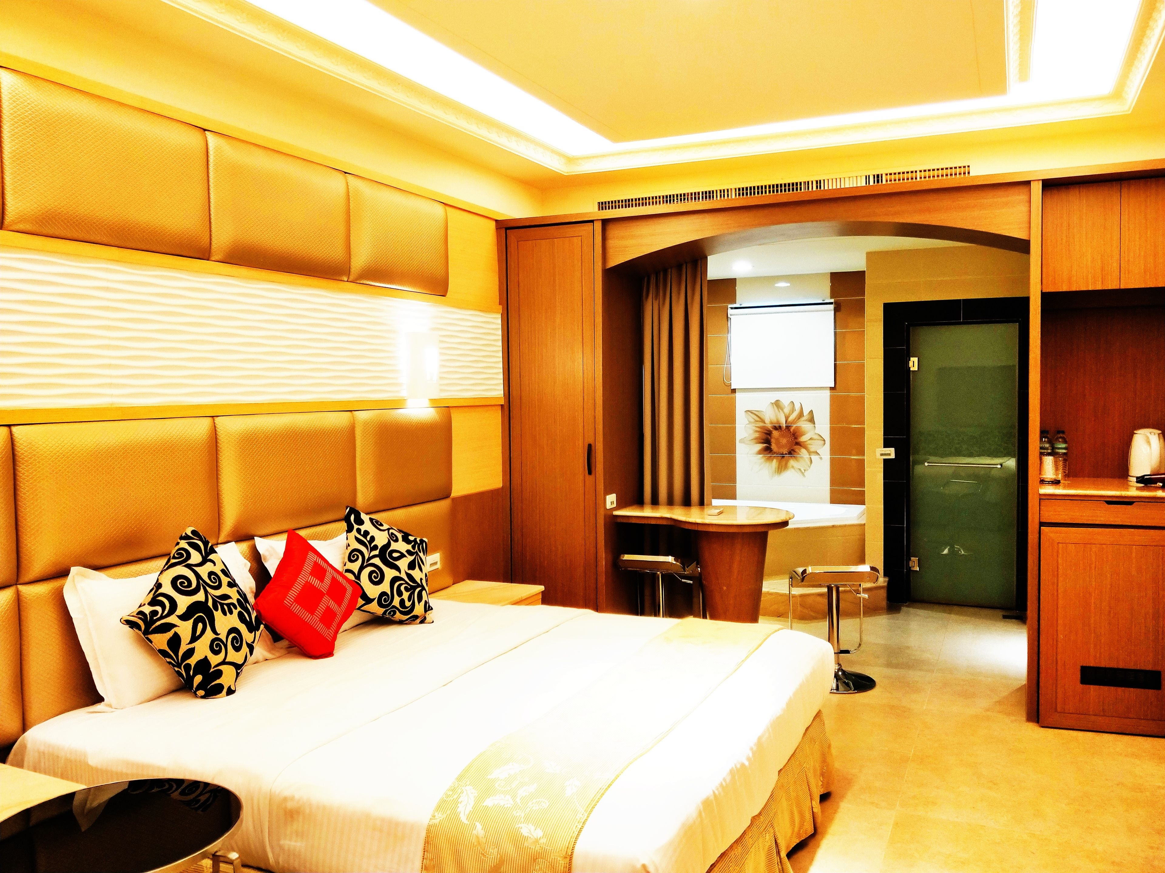 A hotel room with a large bed, a desk, and a kitchenette.
