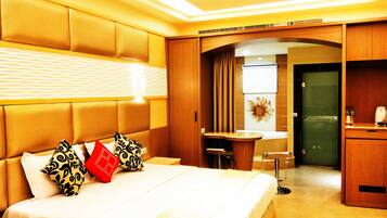 A hotel room with a large bed, a desk, and a kitchenette.