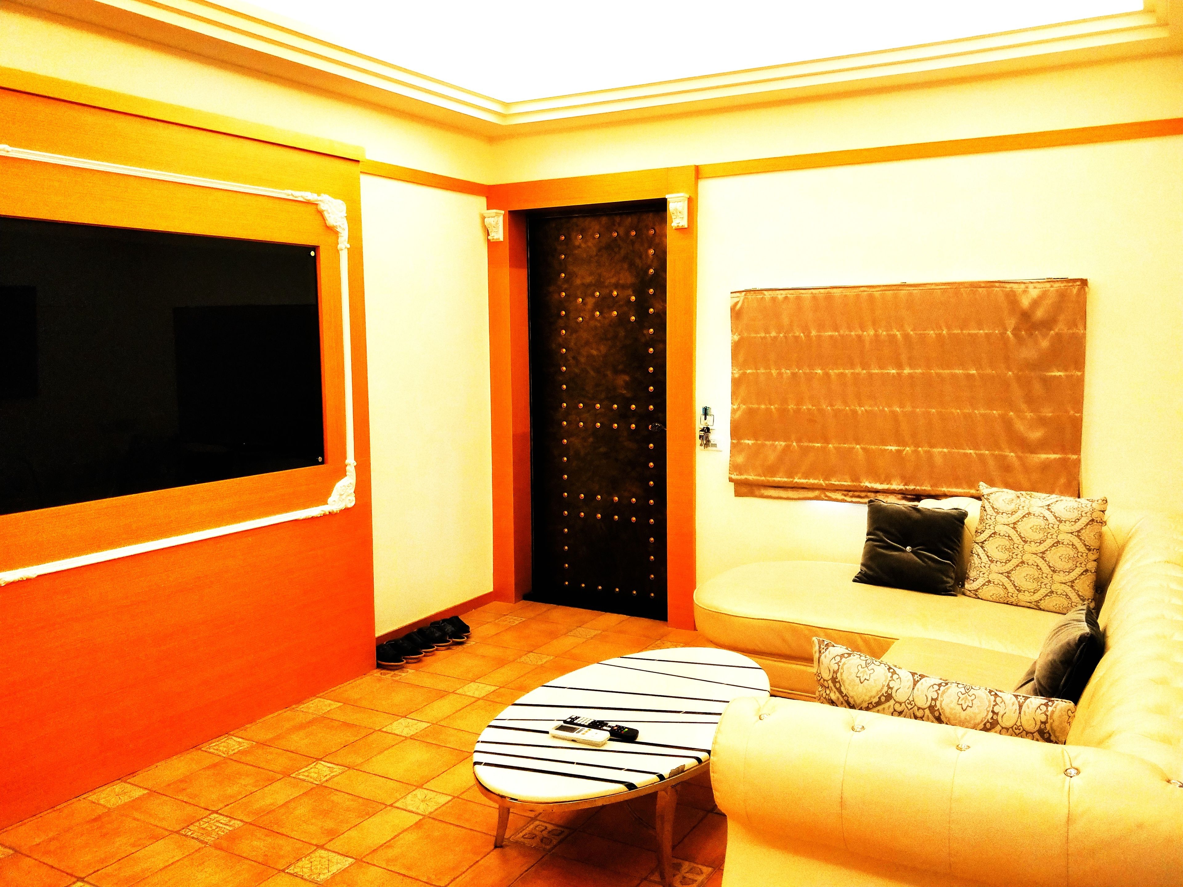 A room with a sofa, a small table, a door, and a window with a blind.