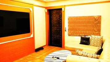 A room with a sofa, a small table, a door, and a window with a blind.