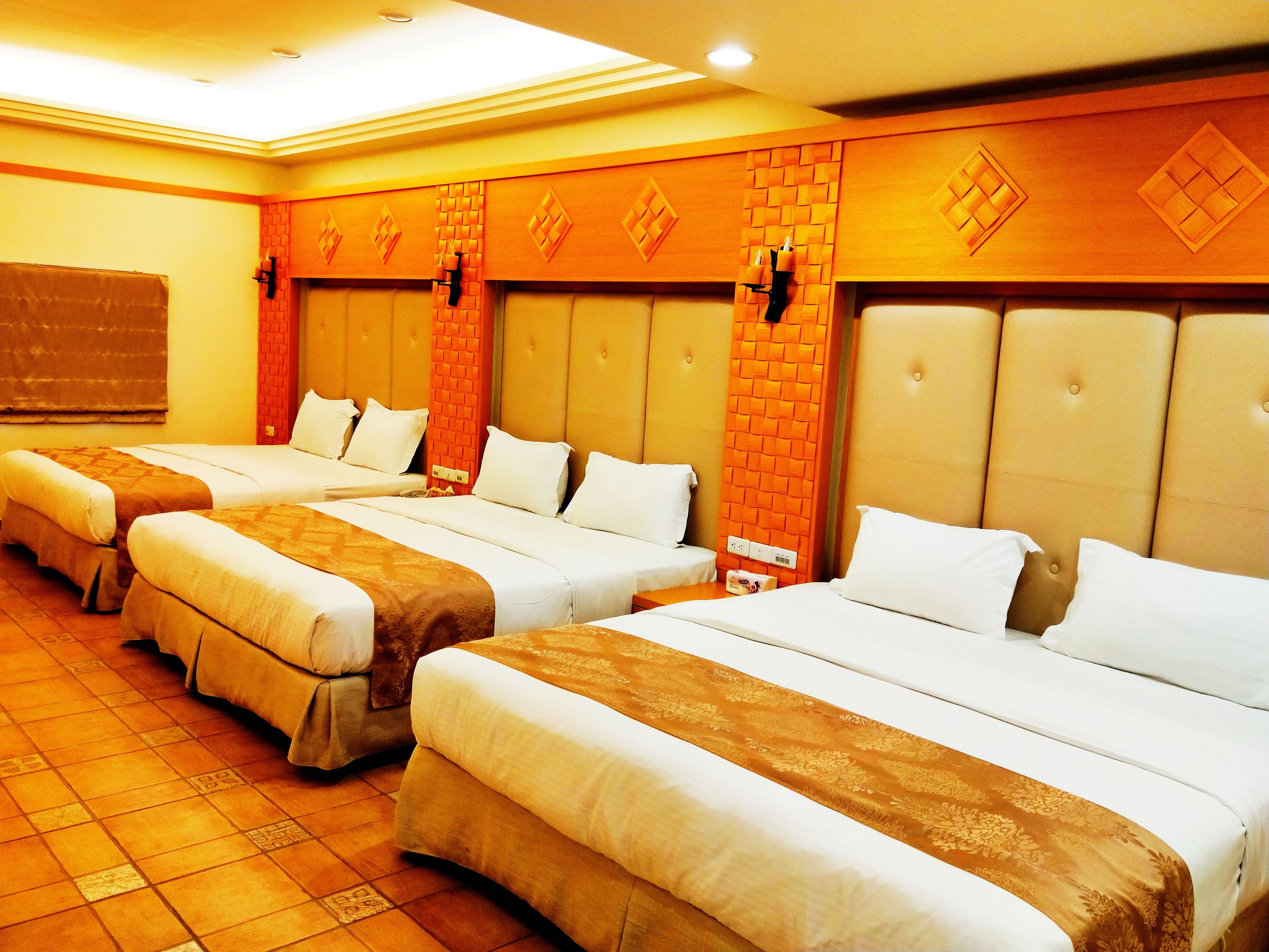 A hotel room with three beds, each with a headboard and white bedding.