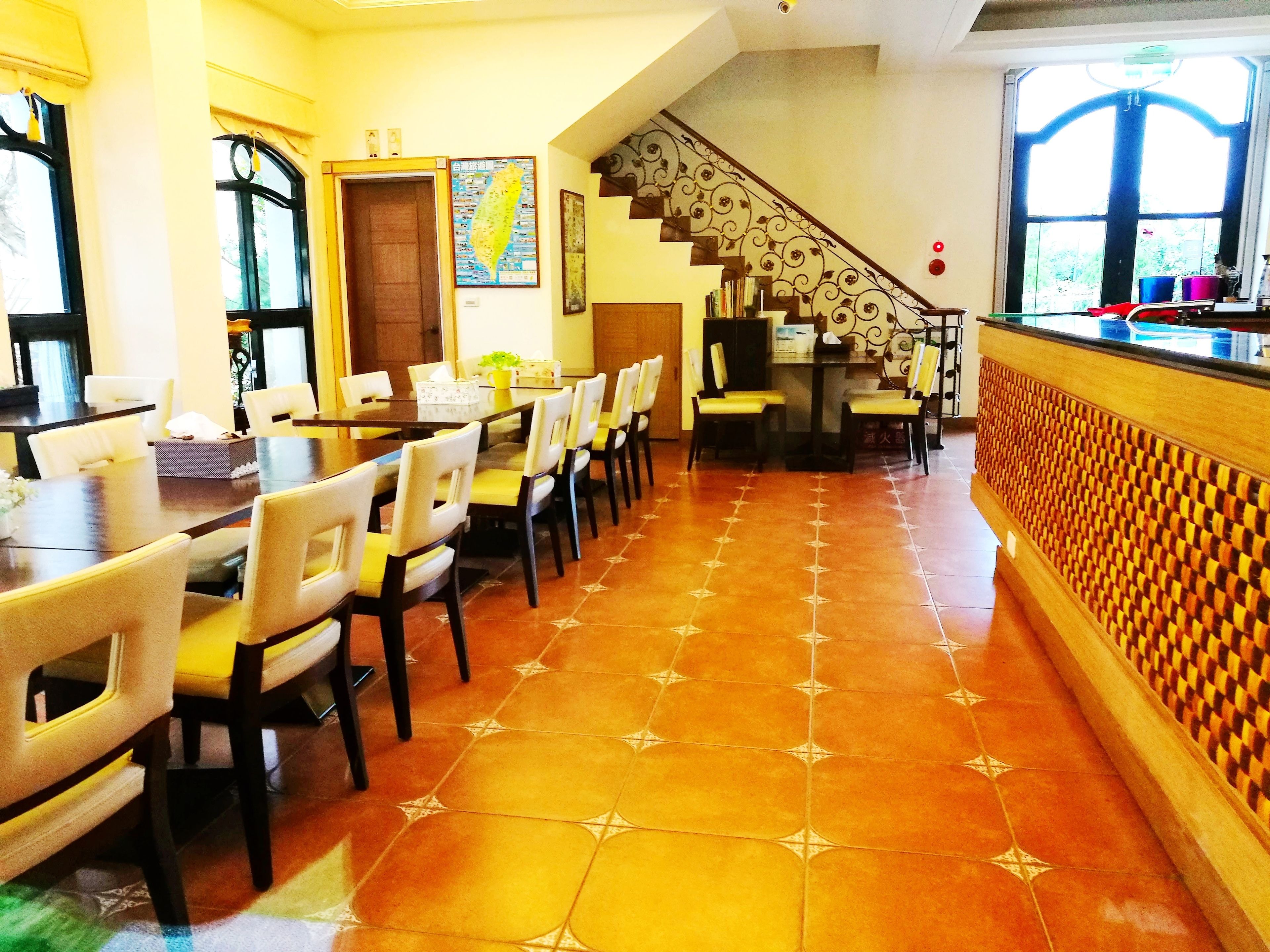A dining area with a long table and chairs, a staircase, and a patterned floor.