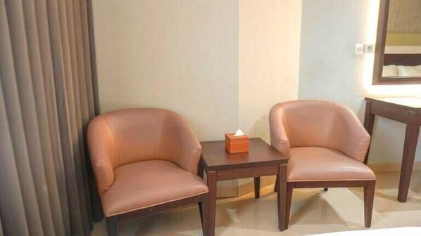 Dos sillones de cuero y una pequeña mesa de madera en una habitación de hotel.