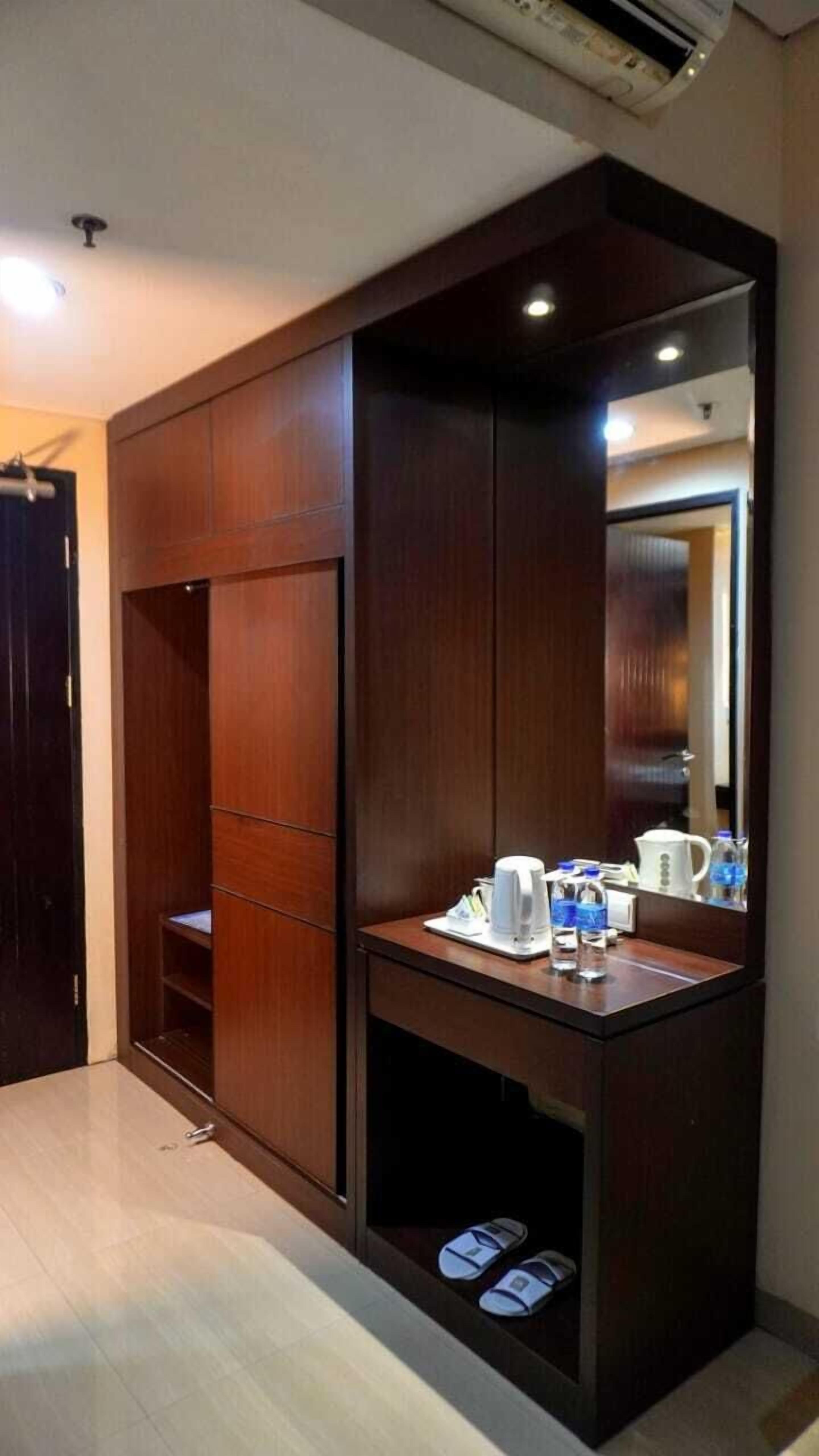 Habitación con armario empotrado, espejo y una pequeña zona de tocador con tetera y tazas.