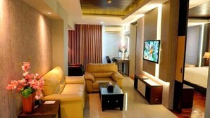 Habitación de hotel con sofá, mesa de centro, televisor y cama.