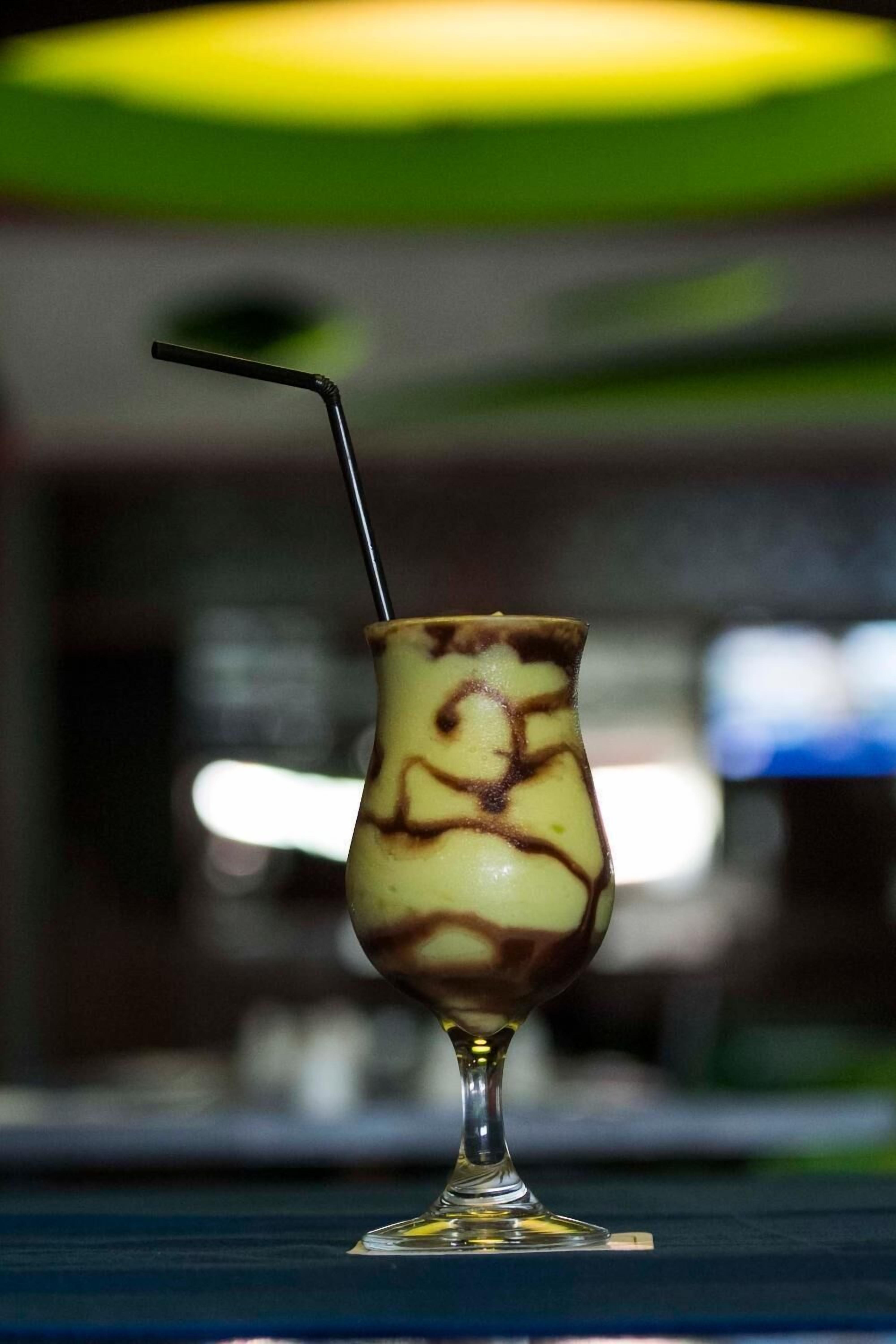 Ein Cocktail im Glas mit Strohhalm auf einem Tisch.