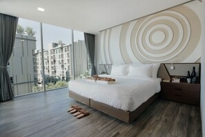 A modern hotel room with a large bed, a wooden floor, a view of the city, and a circular wall design. - Olive Bangkok Hotel (Bangkok)