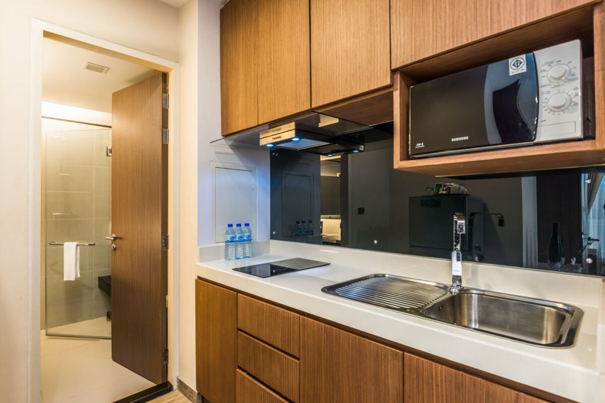 Una cocina moderna con armarios de madera, un lavamanos de acero inoxidable y un microondas integrado.