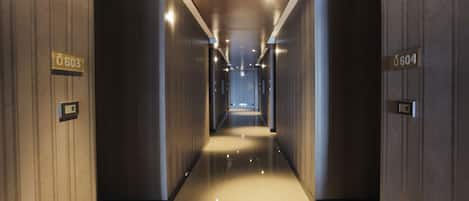 A modern hallway with a polished floor and wooden paneling, featuring illuminated signs with room numbers 603 and 604.