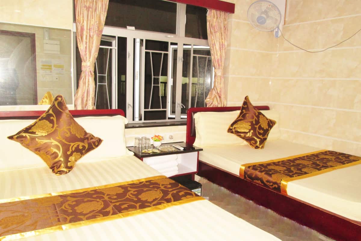 A hotel room with two beds, each with a pillow and a bedside table.