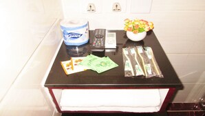A bathroom counter with a toilet paper roll, a remote control, a vase with flowers, and toiletries. - New Reliance Inn (Kowloon)