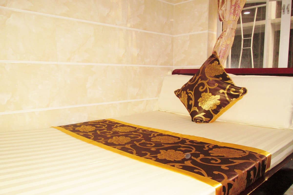 A neatly made bed with a patterned bedspread and a decorative pillow.