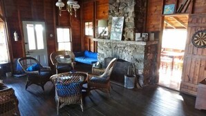 Un interior rústico con paredes de madera, chimenea de piedra, muebles de mimbre y un dardo.