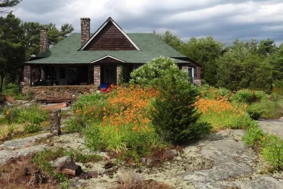 A lodge with a stone chimney, a green roof, and a stone porch.