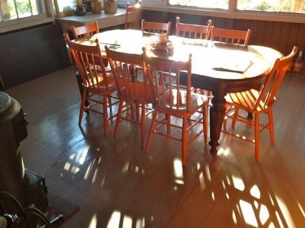 A dining area with a round wooden table surrounded by six wooden chairs.