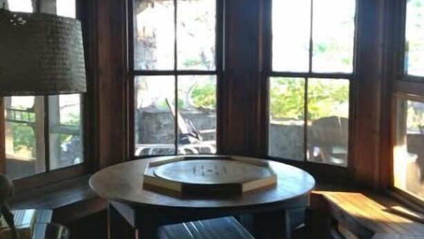 Un interior rústico con una mesa redonda, bancos y una lámpara colgante.