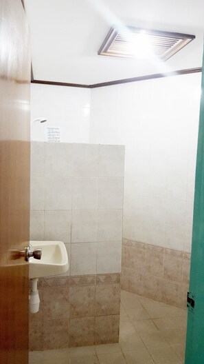A bathroom with a sink, tiled walls, and a ceiling vent.