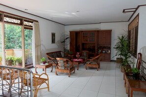 A spacious living room with wooden furniture, a fan, and potted plants. - Pondok Asri Family Guest House (Surabaya)