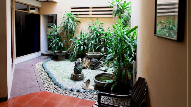 A courtyard with potted plants, a small pond, and a statue. - Pondok Asri Family Guest House (Surabaya)