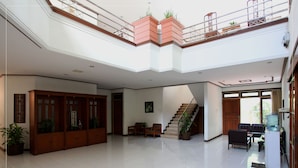 A spacious, multi-level interior with a staircase, seating area, and a water dispenser. - Pondok Asri Family Guest House (Surabaya)