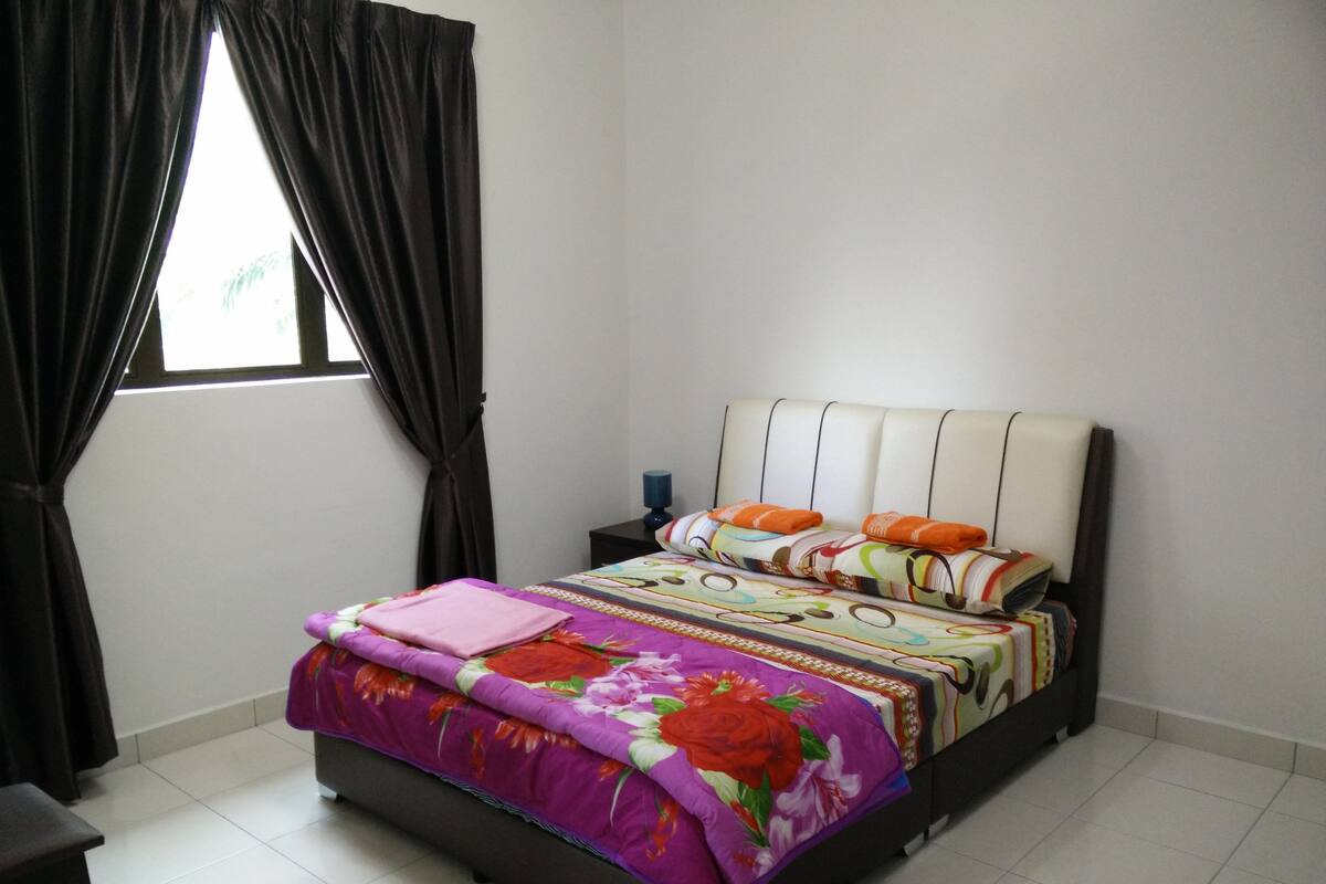 A bedroom with a bed, curtains, a nightstand, and a window.