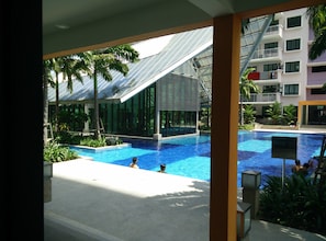 A swimming pool with people, surrounded by palm trees and modern buildings. - Indah Alam Vacation Home (Shah Alam)