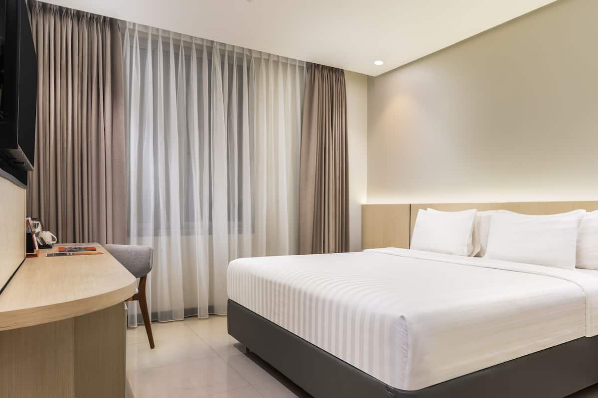 Ein modernes Hotelzimmer mit einem großen Bett, einem Schreibtisch und einem Sessel.