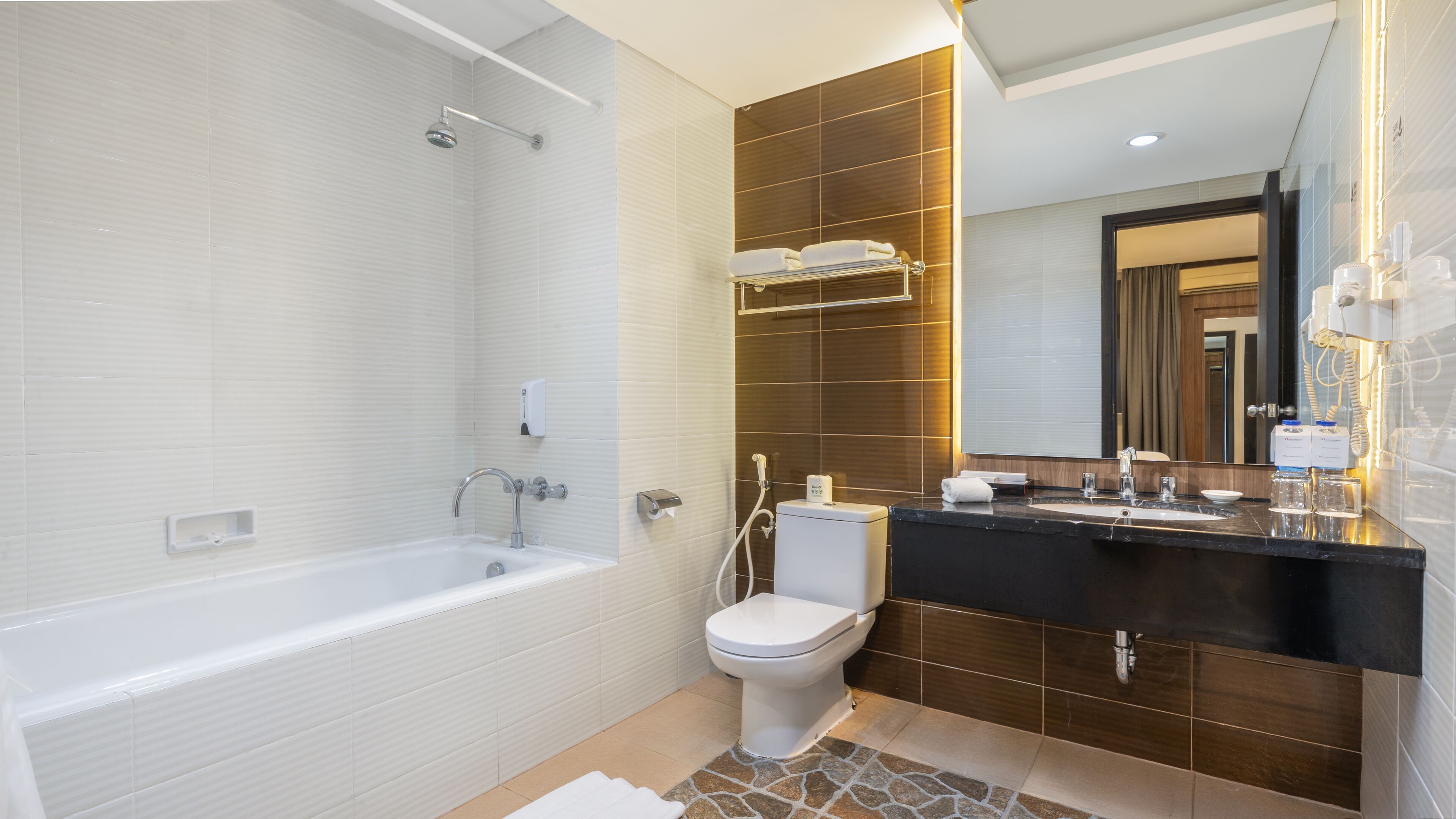 A modern bathroom with a bathtub, toilet, and vanity with a mirror.