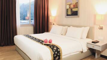 A hotel room with a large bed, a bedside table, a nightstand, a window with curtains, and a wall-mounted artwork.