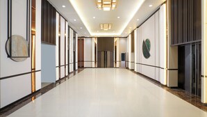 Ein moderner Hotelgang mit poliertem Boden, eingelassener Beleuchtung und dekorativen Wandverkleidungen.