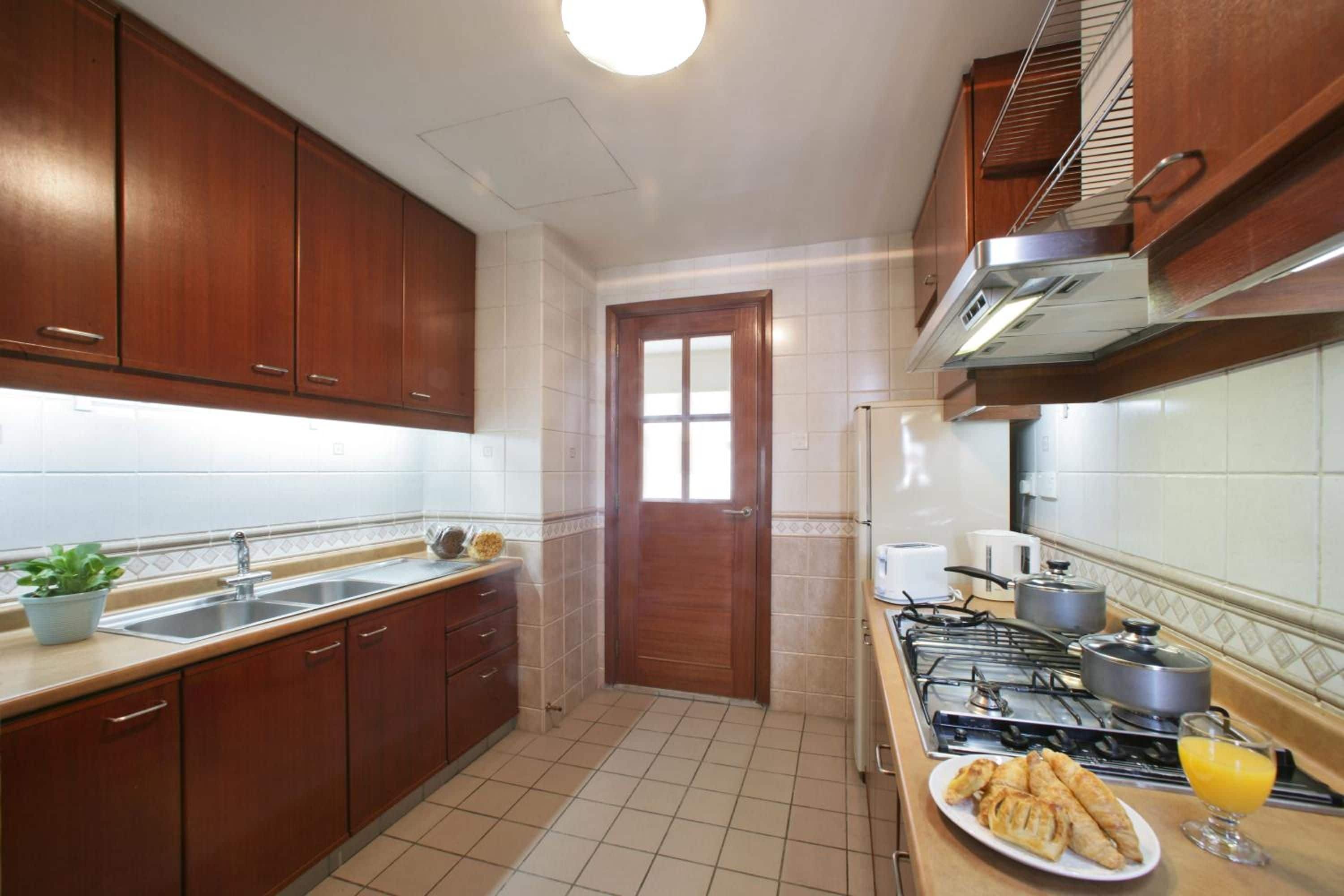 Una cocina con armarios de madera, un lavamanos, una estufa y un ventanal.