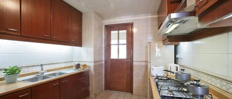 A kitchen with wooden cabinets, a sink, a stove, and a window.