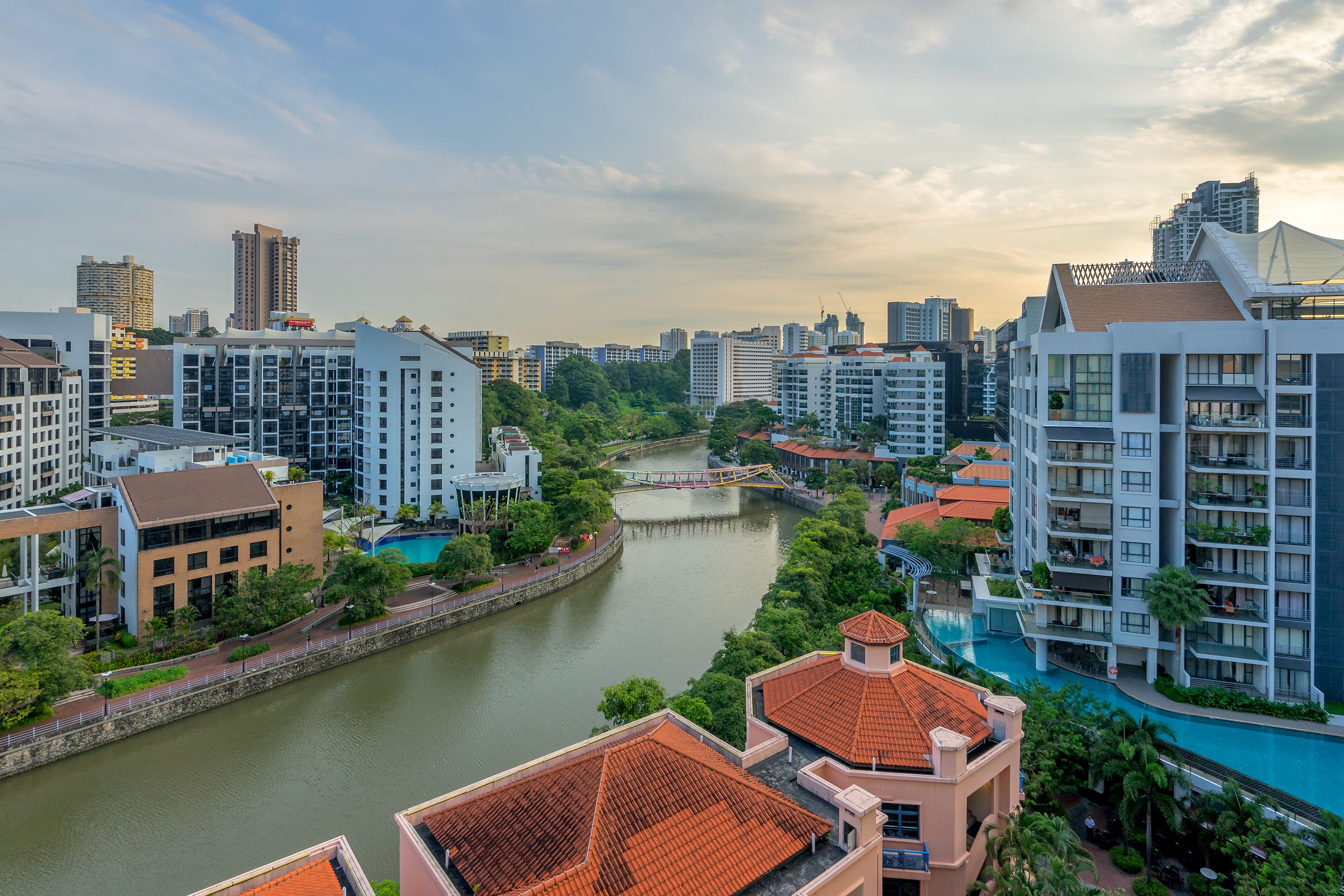 A modern urban hotel with multiple high-rise buildings, a river, and a bridge.