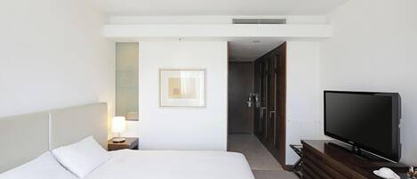 Una habitación de hotel con una cama grande, televisión, escritorio y vestidor.