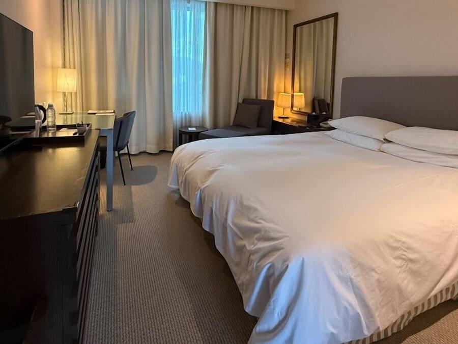 Una habitación de hotel con una cama grande, un escritorio con una silla, un televisor y una lámpara.