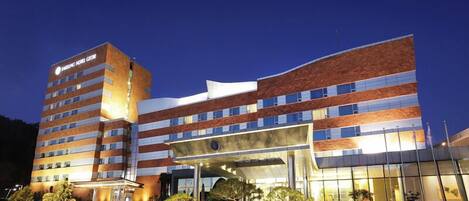 A multi-story hotel with a modern design, featuring a prominent entrance and a well-lit facade.