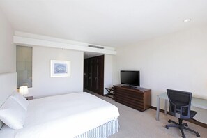 Une chambre d’hôtel avec un lit, une télévision, un bureau et une chaise.