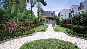 A garden pathway leading to a gazebo with a modern building in the background. - Village Residence Clarke Quay (Singapore)
